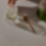 אישה עומדת ומטפחת עץ בונסאי שיושב על משטח פורצלן של אבן קיסר