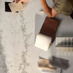 אדריכלית יושבת ליד משטח של אבן קיסר ומחזיקה דוגמאות של אבן קיסר