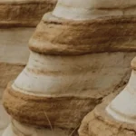 Layered rock formations with distinct horizontal bands and some sparse dry grass.