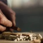 Hands shaping or smoothing clay on a work surface, likely during pottery or crafting.